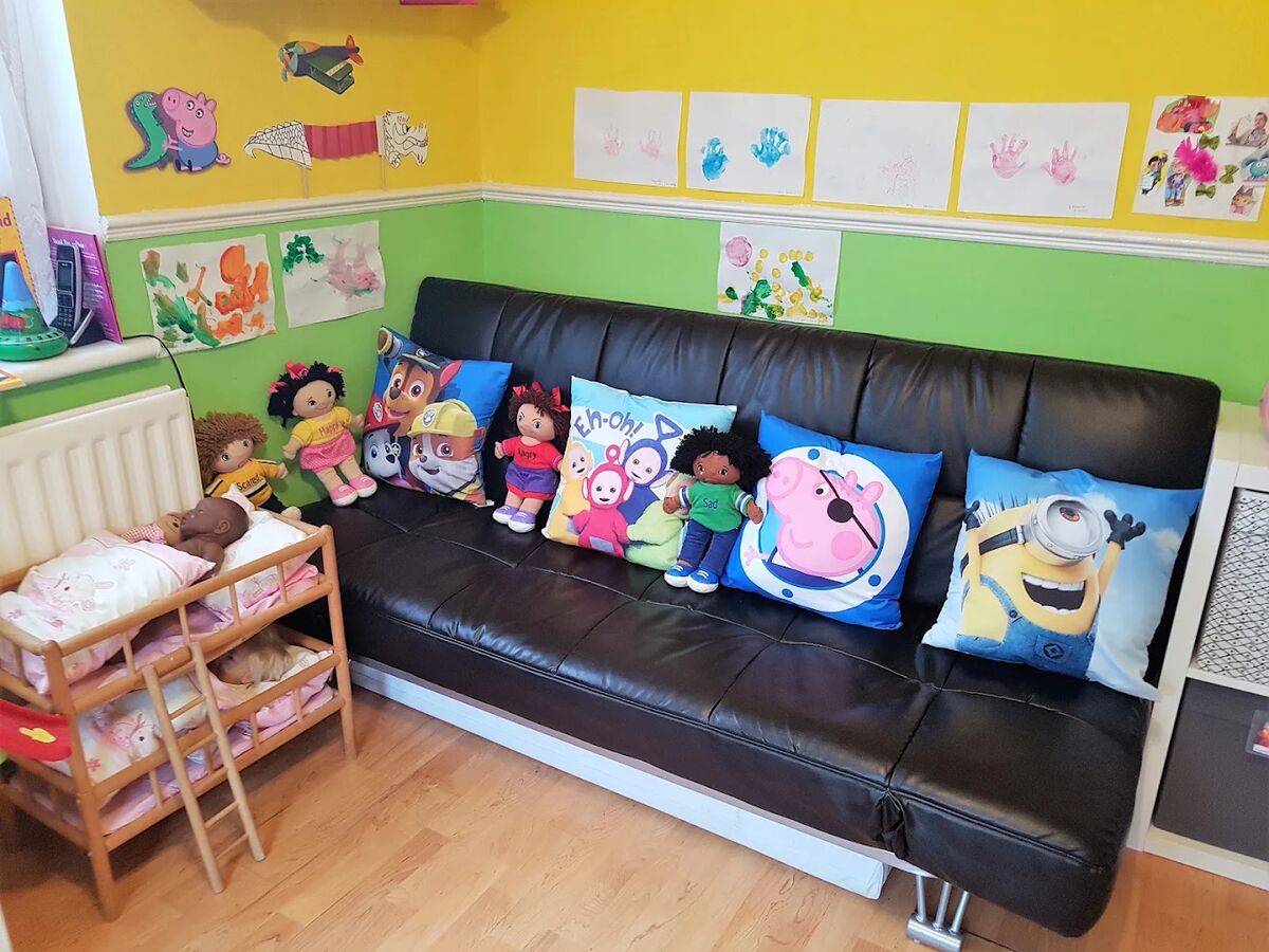 The sofa corner with the children's handprint pictures on the wall above.